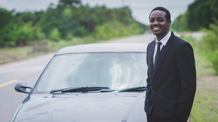 African businessman wearing suit and standing with his black car