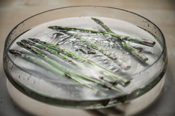 Water washing of fresh asparagus. Asparagus in a bowl of splashing water. Greenery bought at farmer's market.