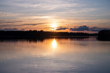 Tranquil golden hour cloud above the forest lake at sunset. Dramatic cloudscape. Symmetry reflections on the water, natural mirror.