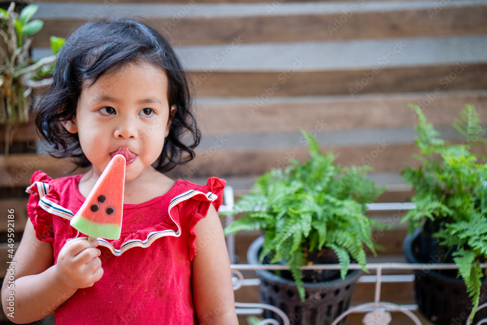 Poster Cute Asian small girl eating watermelon ice-cream