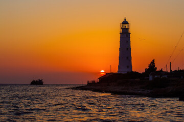 Lighthouse on the sea coast at sunset