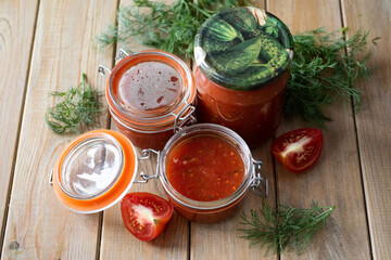 Preservation: spicy homemade ketchup in jars on a wooden table. Close-up