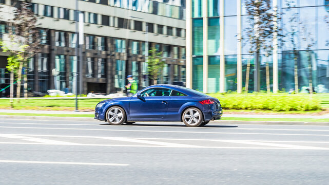 Blue Audi TT Mk2 is driving on high speed in front of modern buildings with glass facade