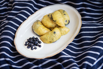 Sweet fruit dumplings with fresh forest blueberries. Homemade fresh dumplings on a beautiful plate with sour cream.