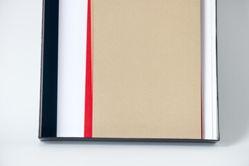 beige, red, and white papers in a black paper box - background with plenty of space for copy