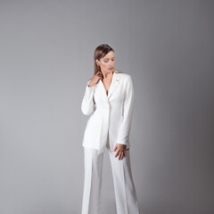 Young stylish lady in a white pantsuit, portrait in the studio.