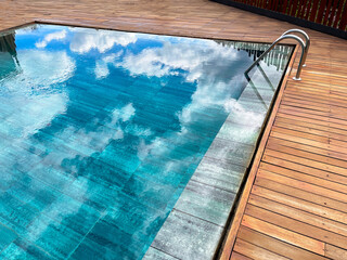 rimless pool, with the exterior surrounded by teak wood, deep blue crystal clear water, swimming...