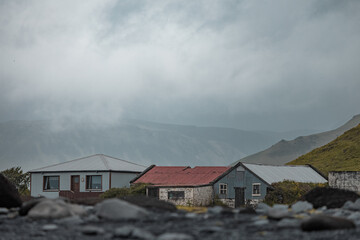 Fototapeta na wymiar Typical houses at the reynisfjara beach in iceland, low profile picture of icelandic houses in front of a majestic cloudy mountain.