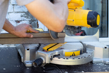 The craftsman sawed a wooden board with a circular miter saw.Woodworking with a professional tool.