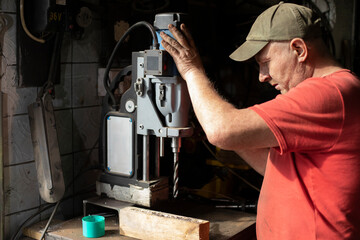 A man installs a drilling machine. The guy in the workshop is setting up the equipment.
