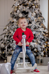 Little boy riding a cardboard horse near the Christmas tree
