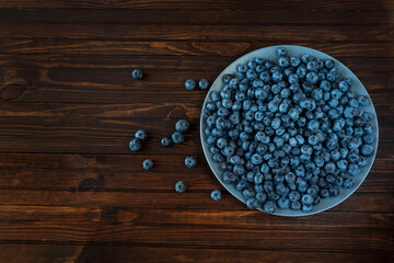 Plate of blueberries on dark wooden background