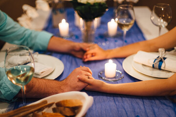 Romantic wedding dinner in the light of candles. Bride and groom holding hands