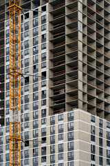 View of frame part of metallic crane machinery attachment at windows of new residential building construction site