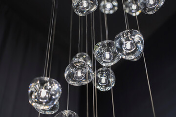Modern hanging lamp lights with black background. Close-up view of crystal balls of contemporary chandelier