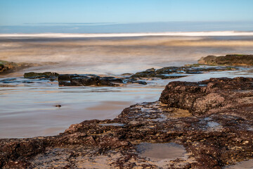 Fototapeta na wymiar Sand, rocks and waves in a beach
