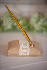 Burlap and lce. pen holder with gold pen at wedding guest sign in table