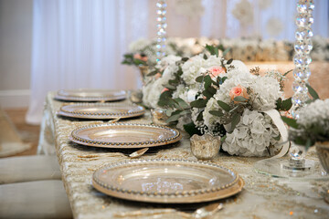 Gorgeous table lanscape filled with lined up gold charger plates, flowers, and crystal vases at wedding reception