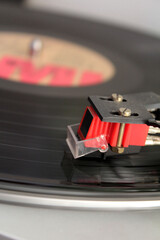 Primer plano de la c&aacute;psula de un tocadiscos, sobre un disco de vinilo en movimiento.