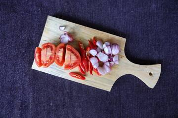 chopped herbs on a wooden cutting board. chili, onion, garlic and tomato