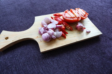 chopped herbs on a wooden cutting board. chili, onion, garlic and tomato