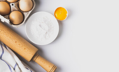 Top view of baking and cooking ingredients. Flour and eggs, rolling pin on grey background. Bakery background frame. Copy space place. Flat lay.