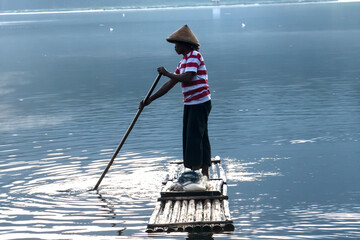 person on the boat, fisherman on a bamboo raft. crossing the lake by boat