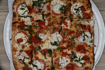 Overhead view of margaritta pizza loaded with tomato toppings and a crispy crust for a full family...