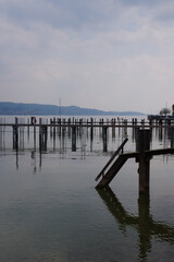 Bootsanlegestelle und Pier am Bodensee (Deutschland, Europa) bei bedecktem Himmel; die Pfahlkonstruktionen bilden ein interessantes geometrisches Muster; die Stimmung ist ruhig und sehr entspannt