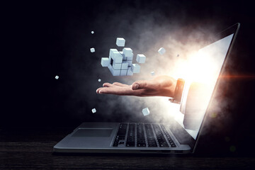 Man`s hand in a laptop and cubes levitating above. Mixed media . Mixed media