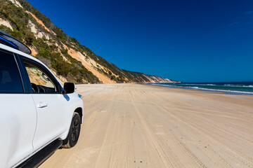 Naklejka premium Off road vehicle on a colourful pristine beach