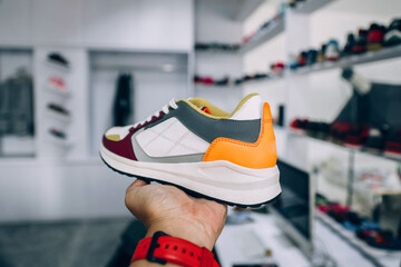 Hand holding sneaker with blurry background of fashion store