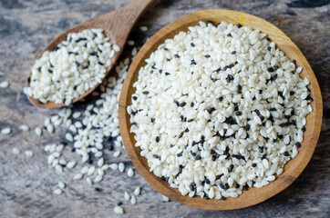 Top view of dry organic mixed white and black seeds in wooden bowl and spoon on grunge background. Concept of healthy food ingredient or agricultural product concept