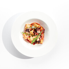Cannelloni pasta with seafood and Parmesan cheese. Lasagna cannelloni pasta stuffed with tomato sauce and fried octopus. Italian pasta in white plate isolated on white background .
