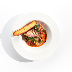 Seafood with tomato sauce on white restaurant plate. Shrimp seafood and tomato stew garnished with fried bread. Isolated on white background.