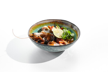 Tom yum or tom yam - hot and sour Thai soup with mixed seafood. Thai traditional soup with shrimps and coconut milk. Tom yum on white background. Isolated soup plate over white background. .