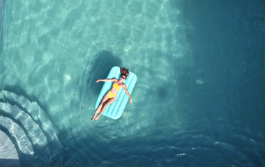 Overhead shot of a young Caucasian female lying on an airbed in the pool