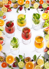 Summer fruit lemonade on white background. Fresh summer drink with fruit frame on white table. Lemonades ingredients frame - citrus fruit, berries and herbs.