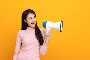 Shout out loud with megaphone. Young beautiful asian woman woman announces with a voice about promotions and advertisements for products at a discounted price. Shopping and fashion concept.
