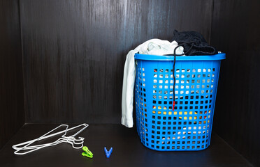 Low light view and copy space. Pile of fold clothes in a basket with beside hanger and pin.