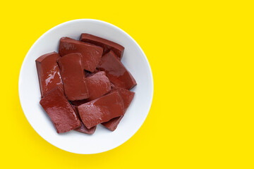 Pork blood pudding in white bowl on yellow background.