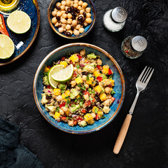 Healthy quinoa black bean salad with mango and avocado. Perfect for spring, summer, fall or winter. Black stone background, top view.	