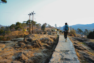 Obraz premium a man walking on a path , mountain hike , house in background 