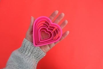 Pink hearts held in hand on red background