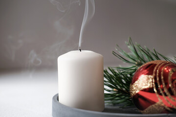 blown out white candle with smoke on a concrete tray with christmas decor. holiday selebration, end...