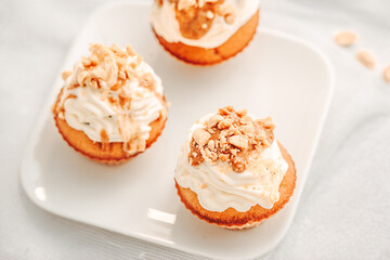 Muffin. Creme muffins with caramel and nuts. Creme on the top of muffin. Caramel muffins.  