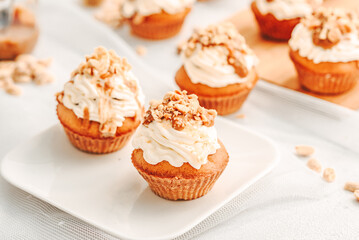 Muffin. Creme muffins with caramel and nuts. Creme on the top of muffin. Caramel muffins.  