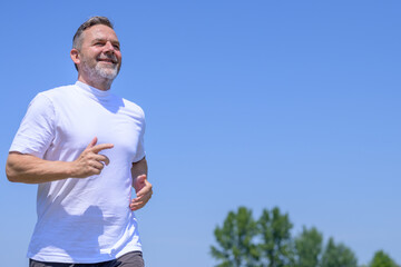 Happy healthy middle-aged man enjoying jogging outdoors