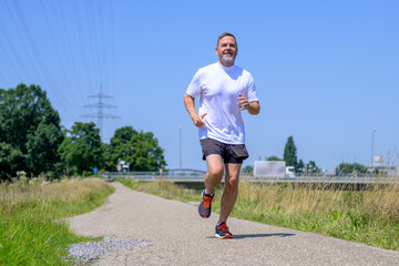 Low angle view of a senior man working out jogging - obrazy, fototapety, plakaty