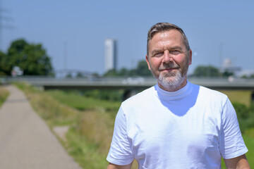Middle-aged bearded man smiling at the camera while out jogging